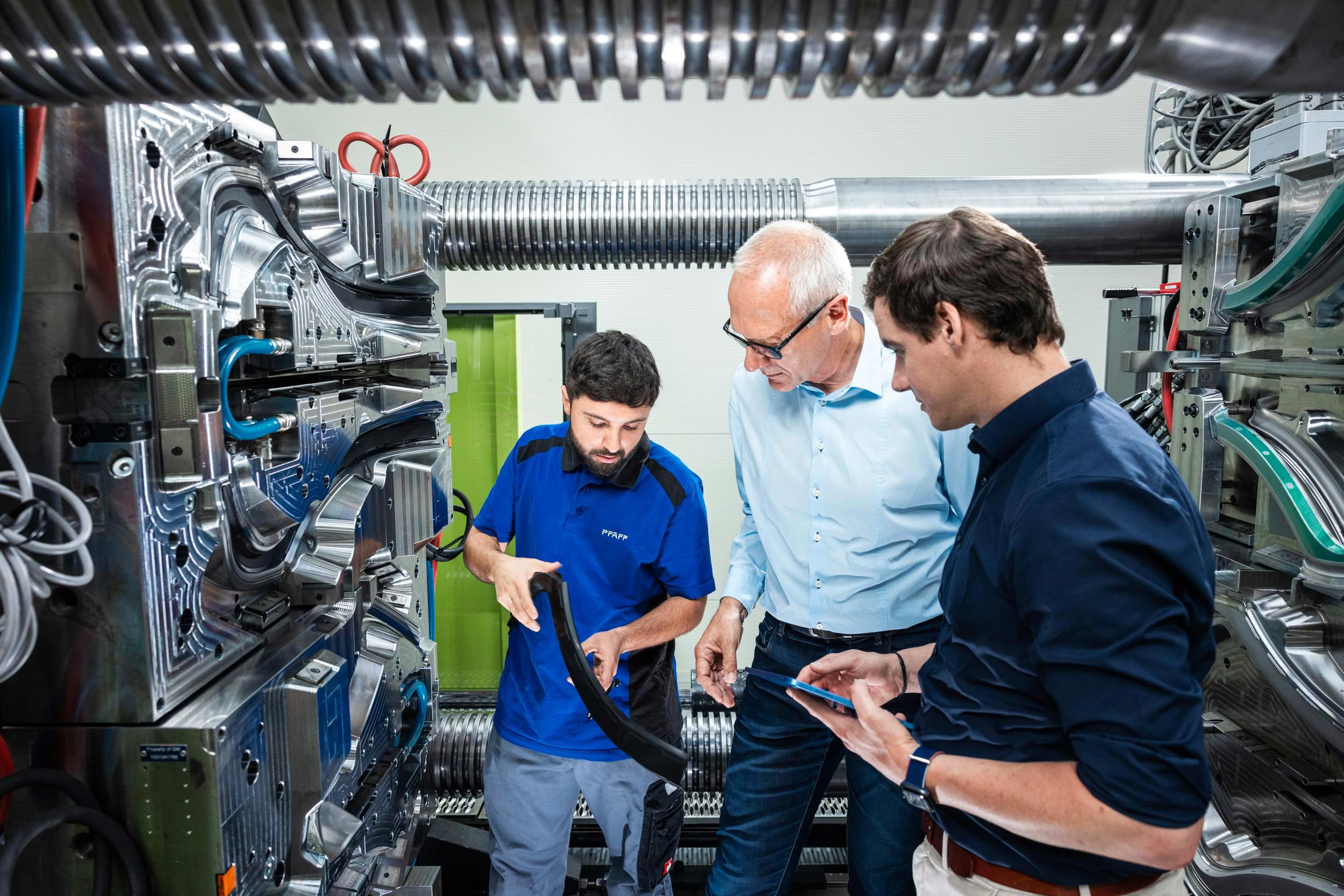 PFAFF team discussing a sealing profile next to an injection molding machine