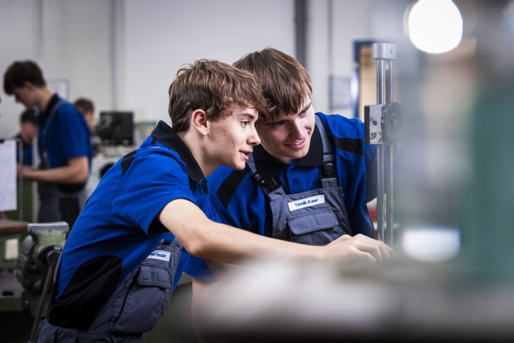 Two apprentices working together at a machine