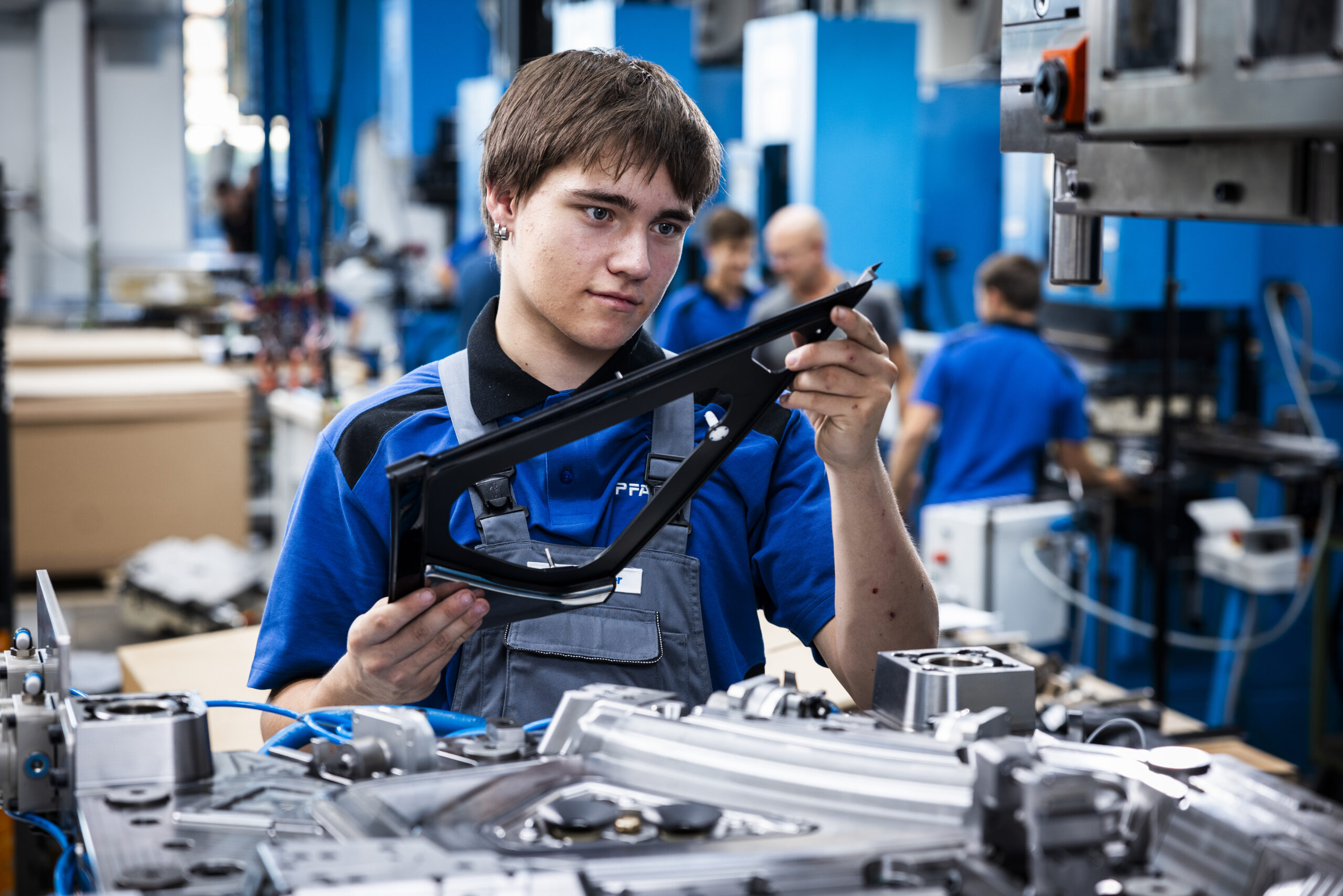 Apprentice holds a plastic component in production
