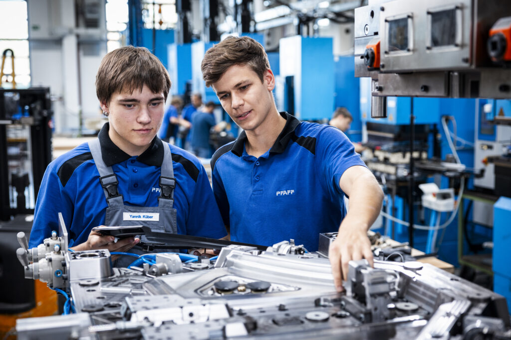 Two apprentices assemble components on a PFAFF mold and toolmaking system