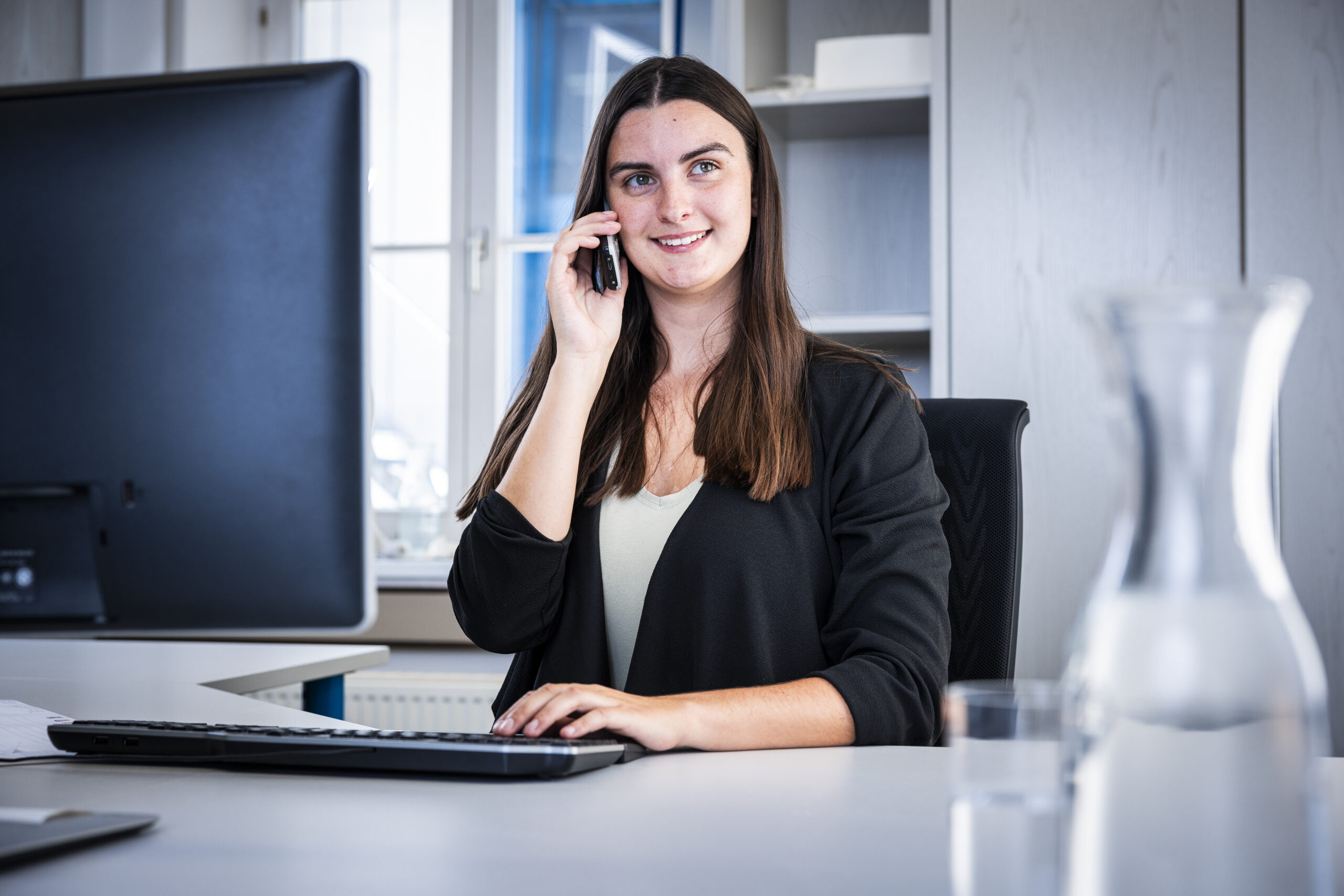 Apprentice on the phone at her desk in the office