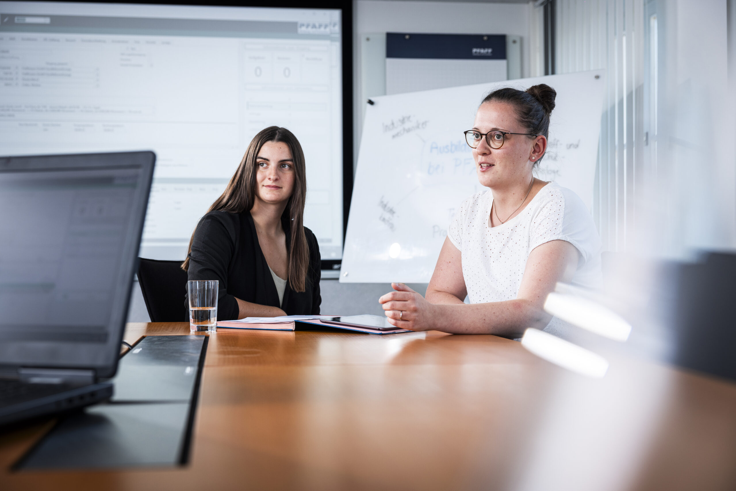 Two female employees discussing documents at a conference table