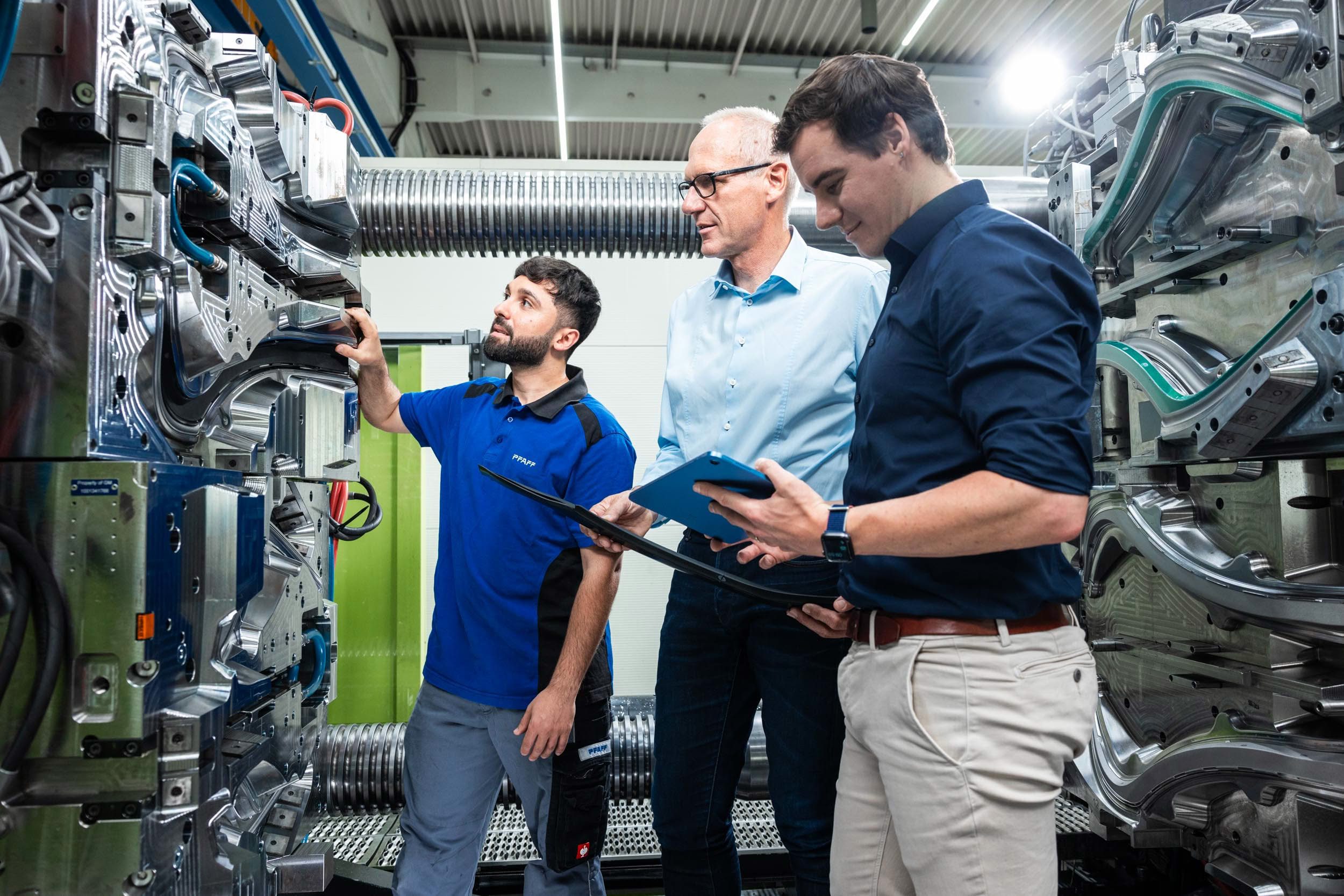 Three colleagues discussing at an injection molding machine