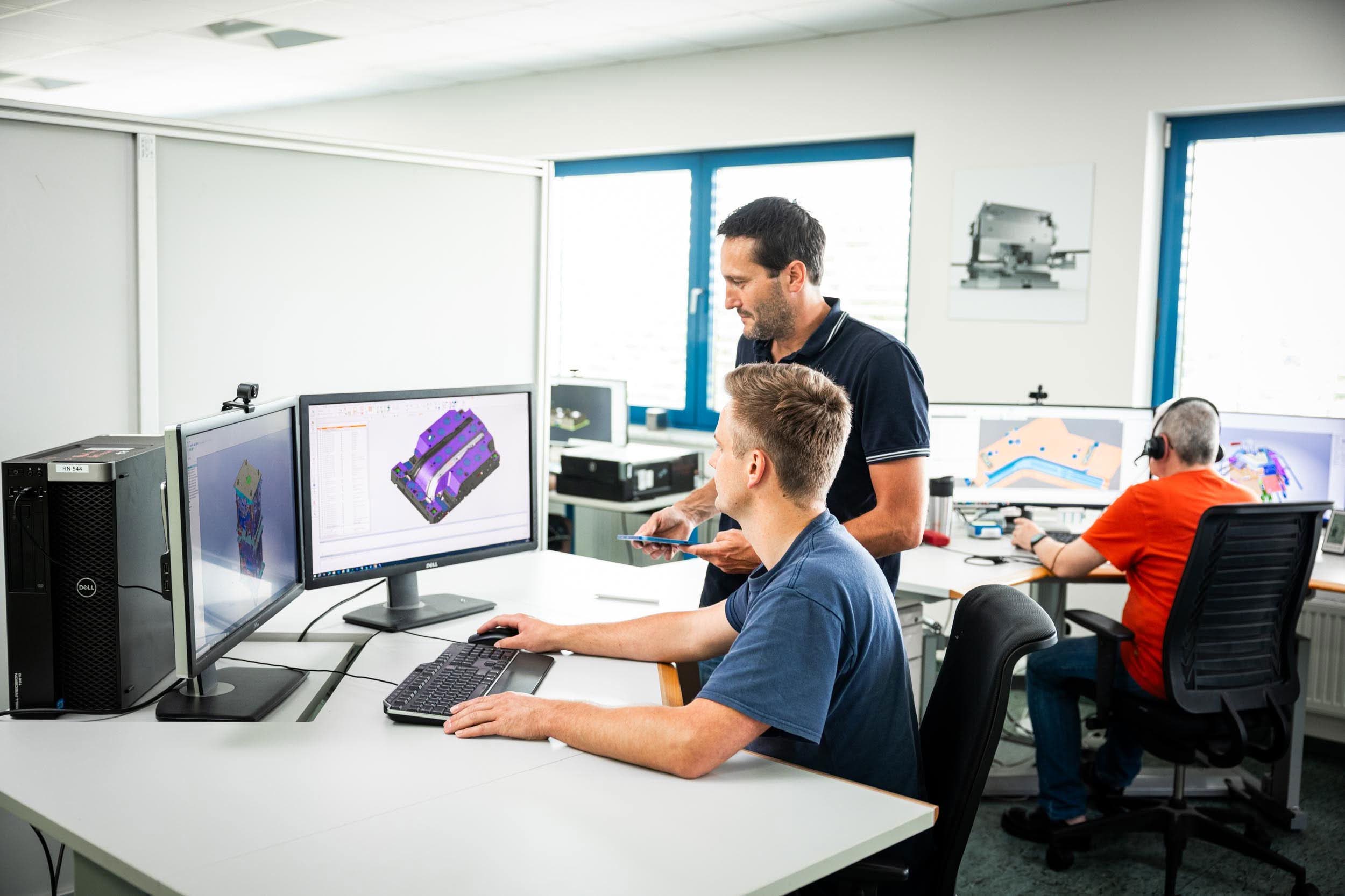 Ingenieure konstruieren eine Form in 3D-CAD-Software an ihren Arbeitsplätzen