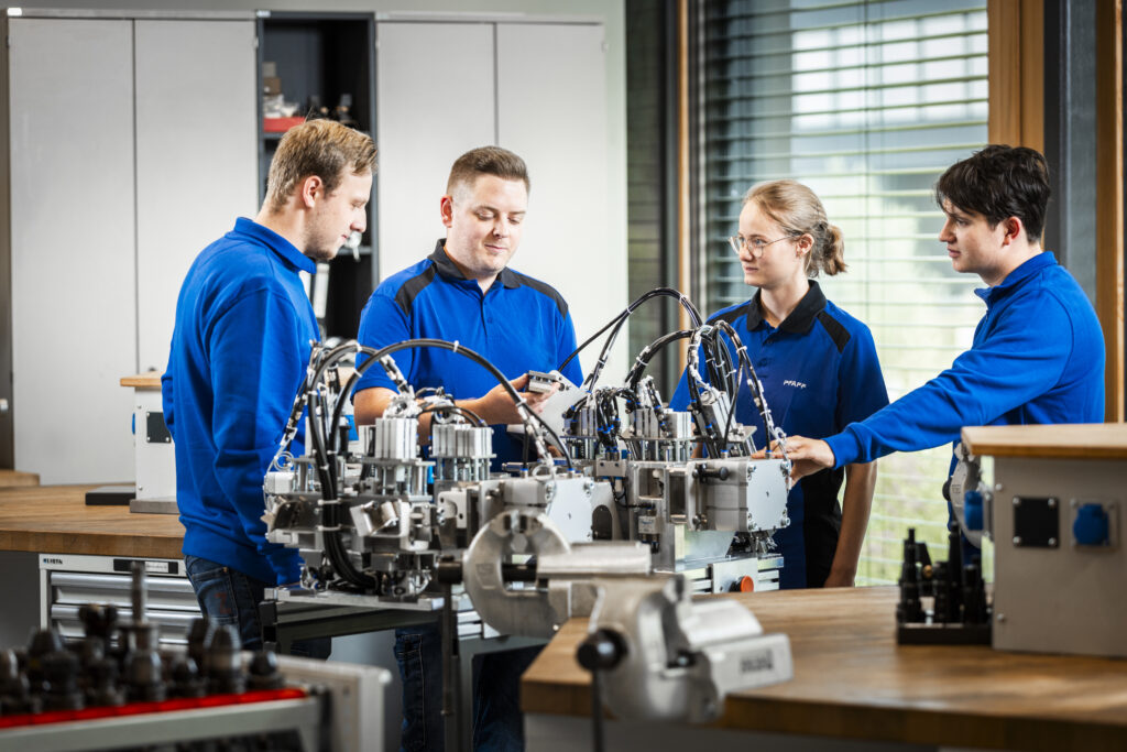 Three apprentices and trainers working together on a test system